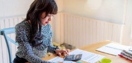 Image of woman sitting at desk using calculator