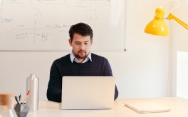 An individual working at their desk with their laptop.